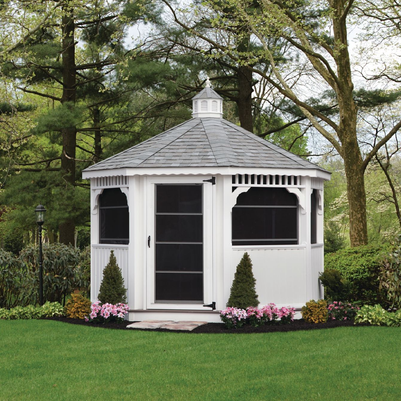 a white gazebo with a screened in door sits in the middle of a lush green yard