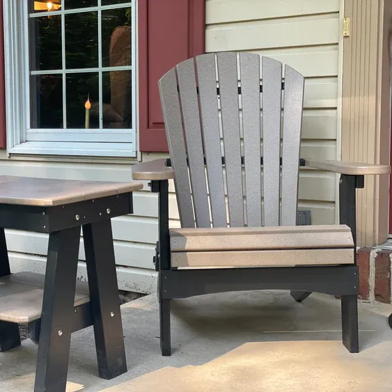 a row of purple and teal adirondack chairs are sitting next to a body of water .