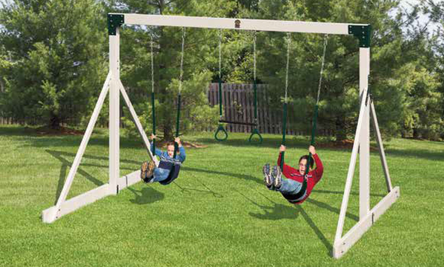 Two children are swinging on a wooden swing set in a yard.