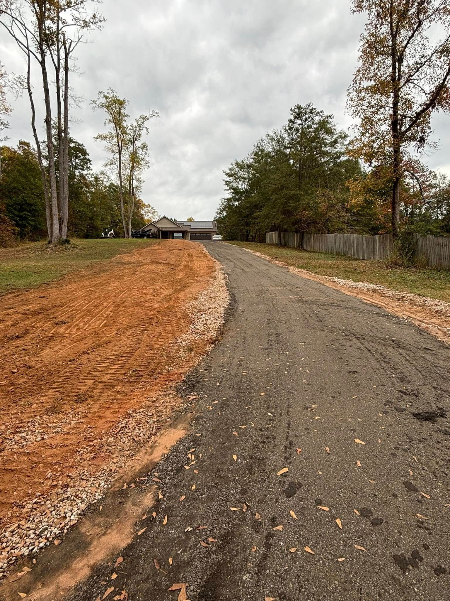 Gravel driveway leading towards a house under an overcast sky
