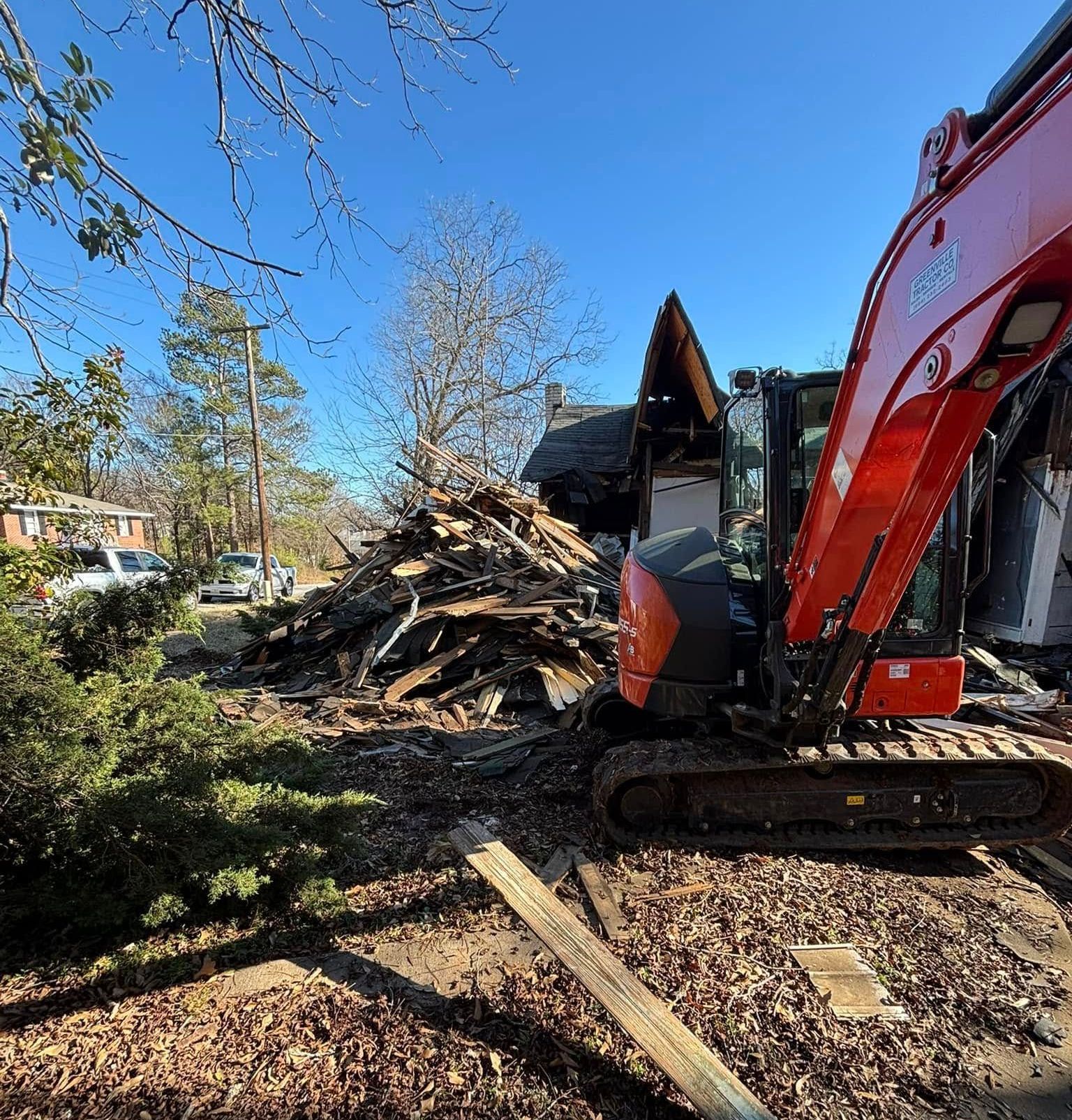 Demolition site with an excavator removing debris, sunny day, blue sky.