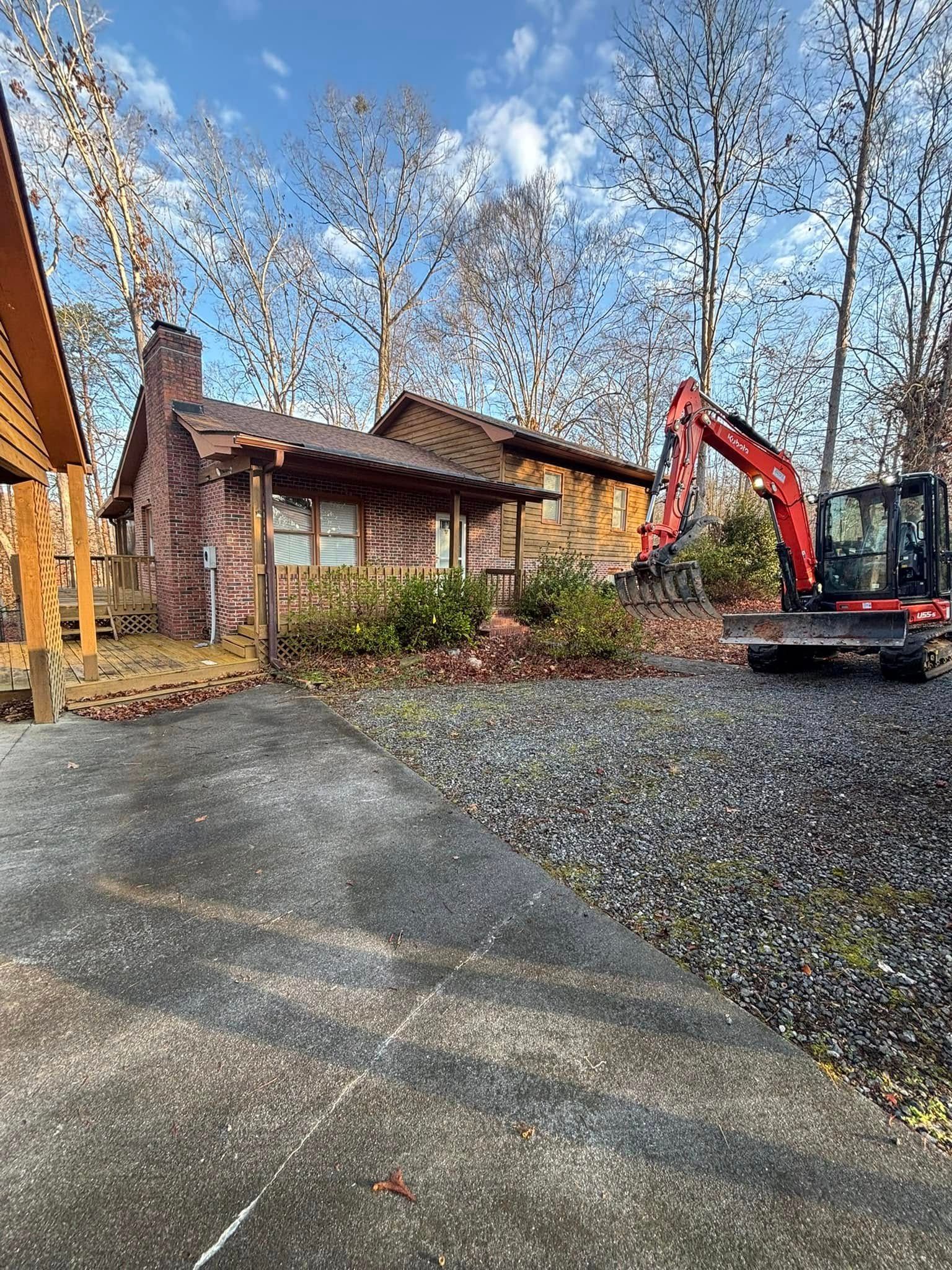 A small brick house is being demolished by an excavator. The house has a chimney and a porch.