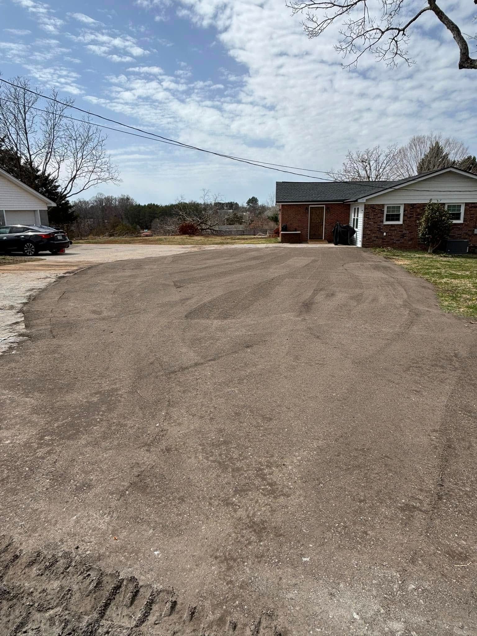 Gravel driveway in front of two houses under a cloudy sky. One house has a red door