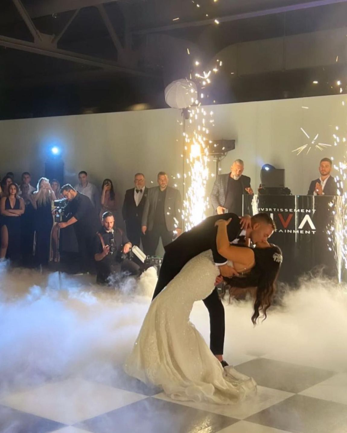 a bride and groom are kissing under a fireworks display at their wedding reception