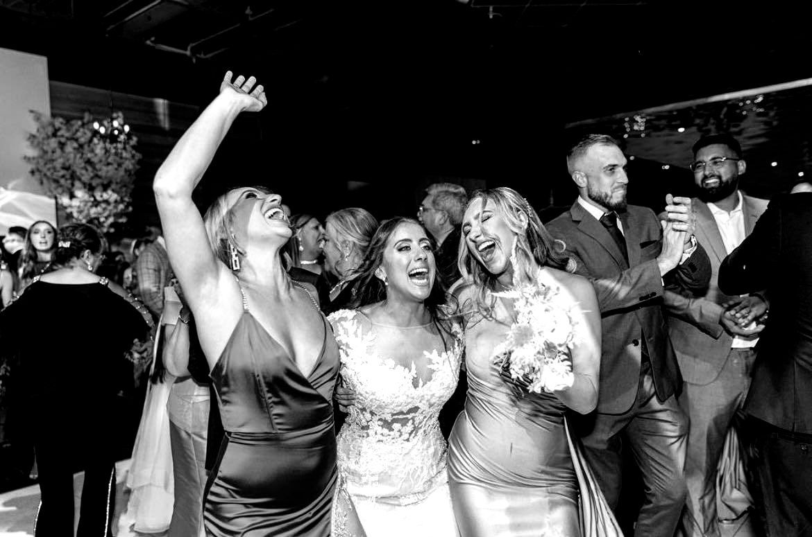 a black and white photo of a group of people dancing at a wedding reception .