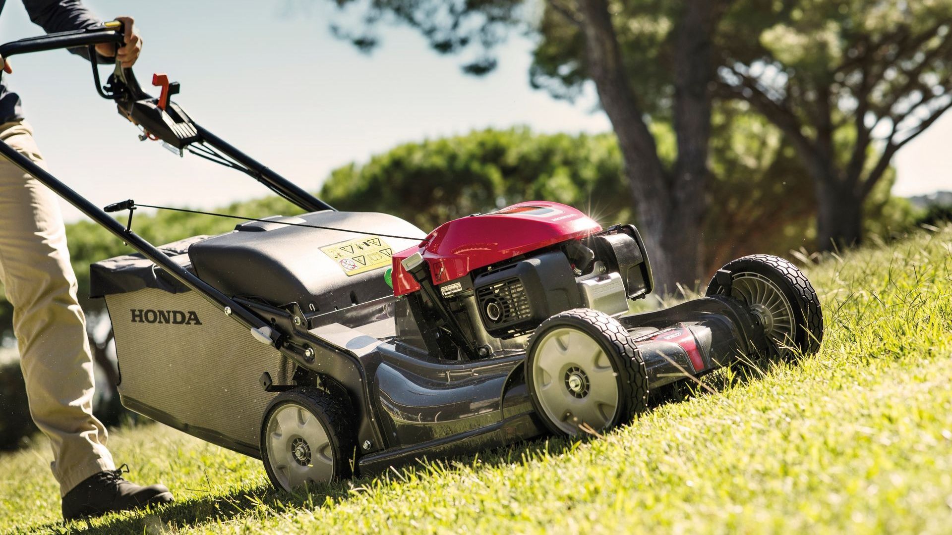 Photograph of a person cutting grass with a Honda HRX lawnmower with polymer cutting deck.