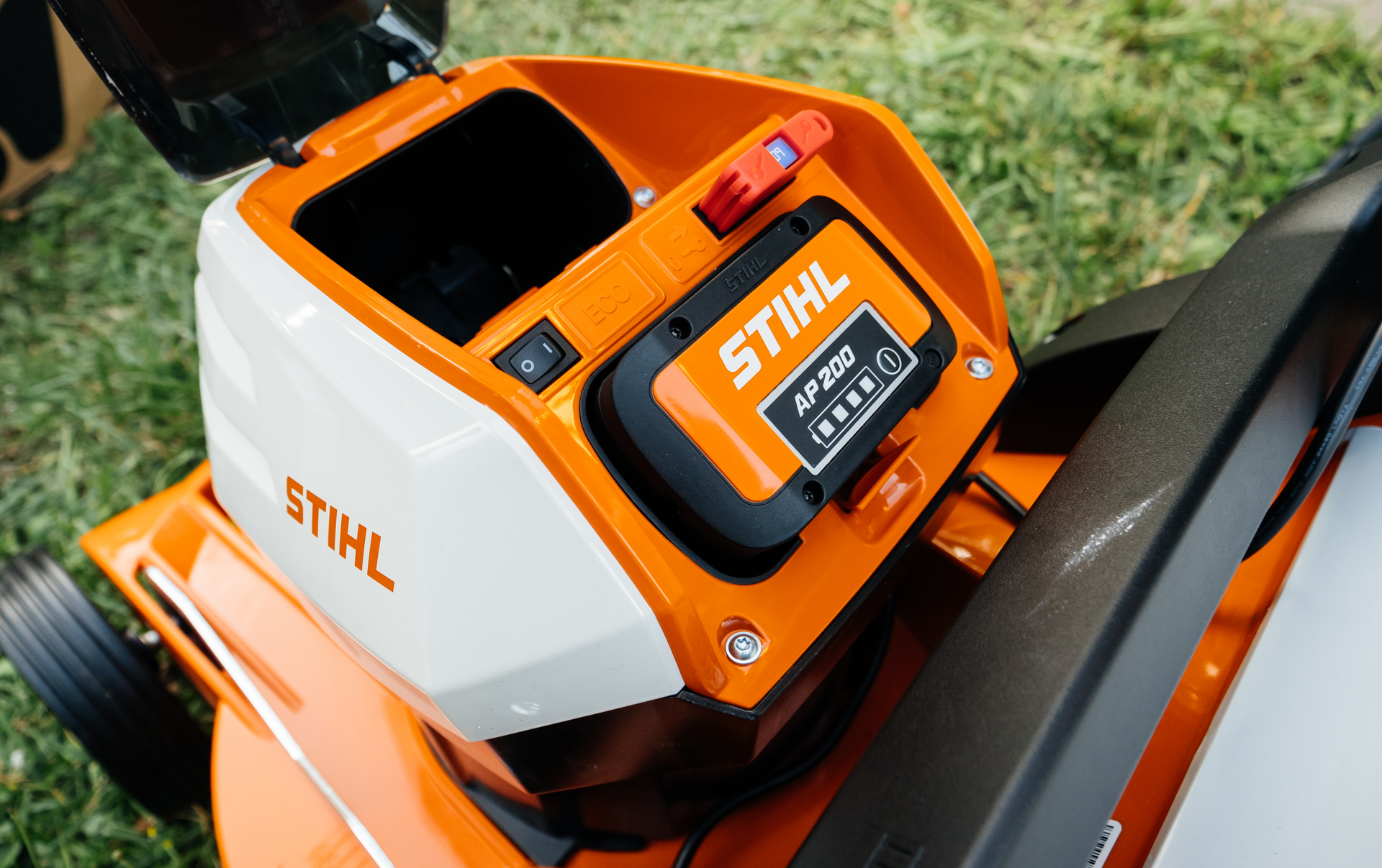 Photograph of a Stihl lithium-ion battery, being inserted into a Stihl cordless lawnmower.