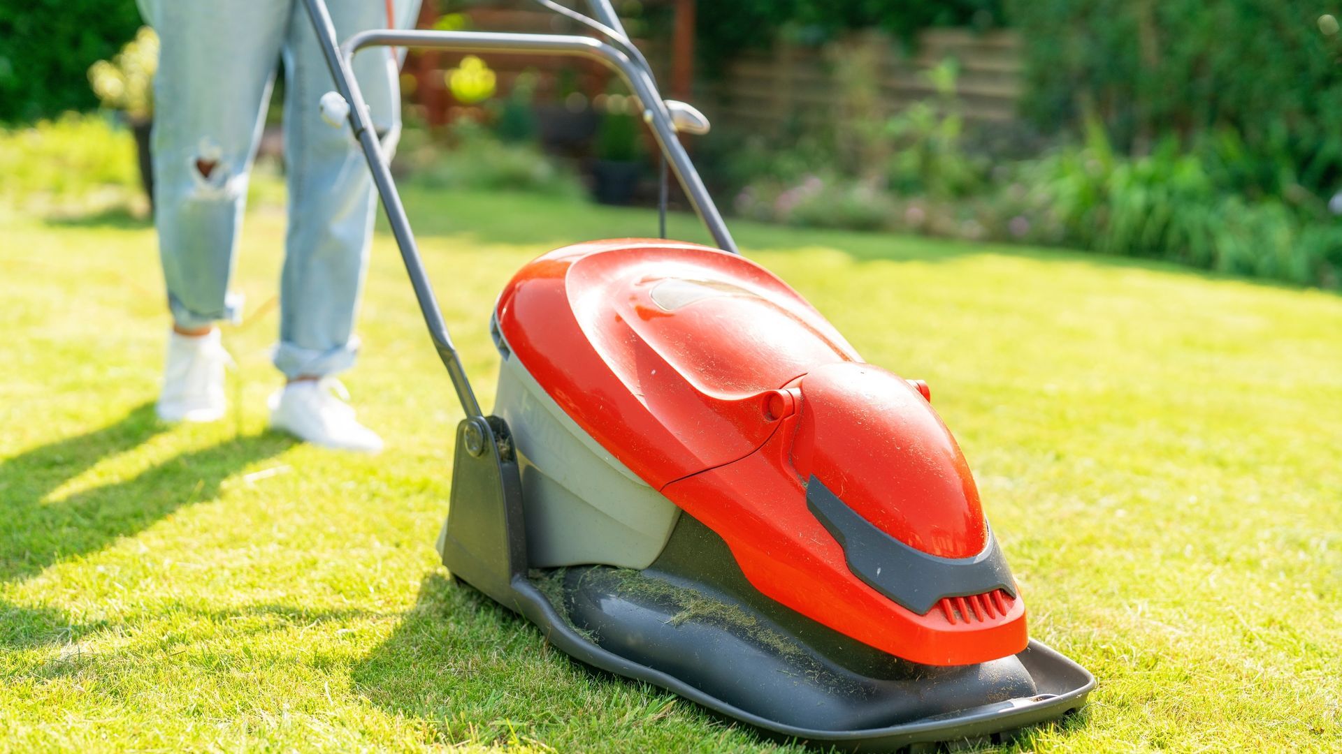 Photograph of a lawn being cut with a corded, electric, Flymo hover mower.