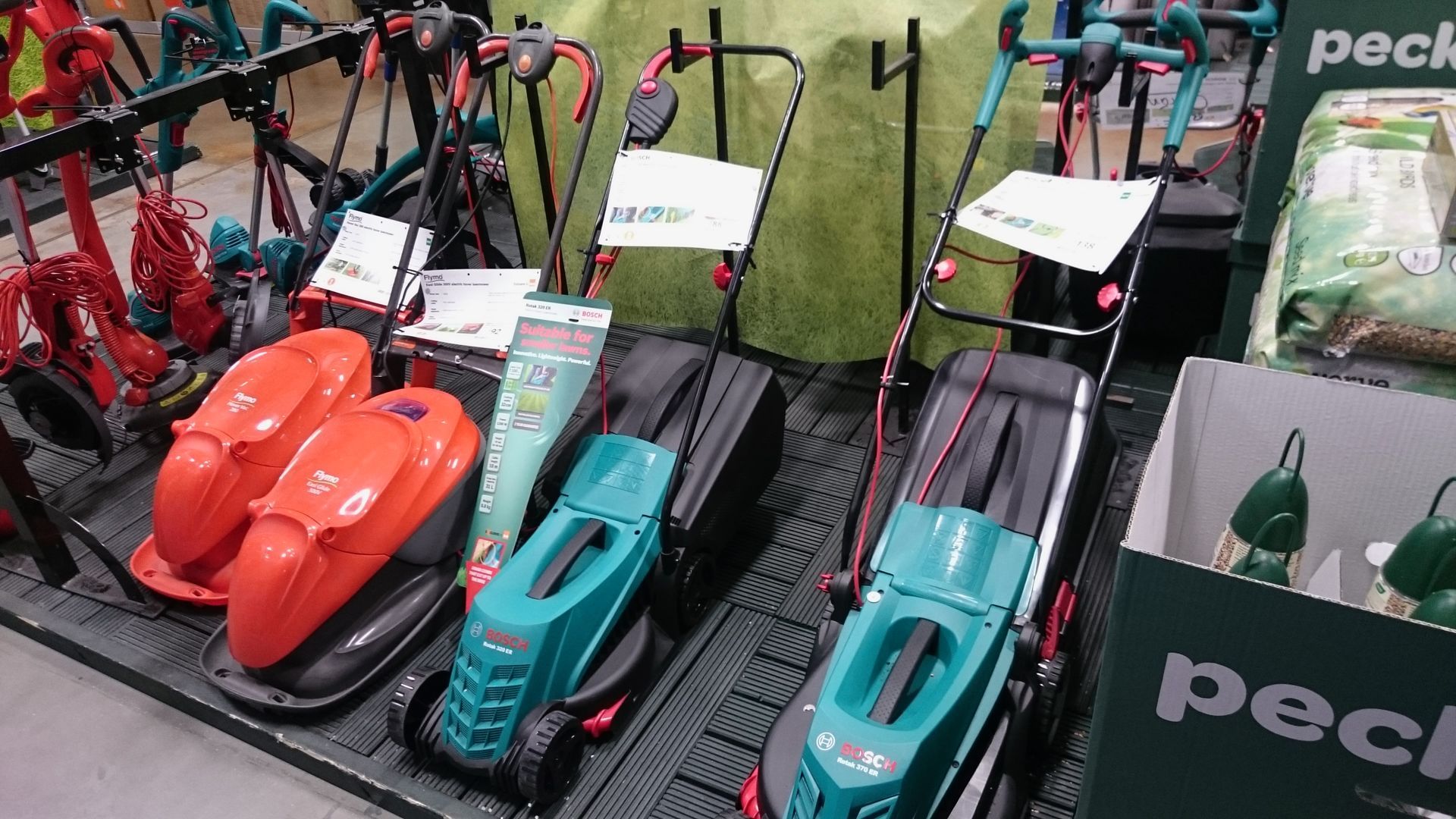Photograph of corded electric hover mowers and corded electric wheeled mowers, on display in a B&Q store.
