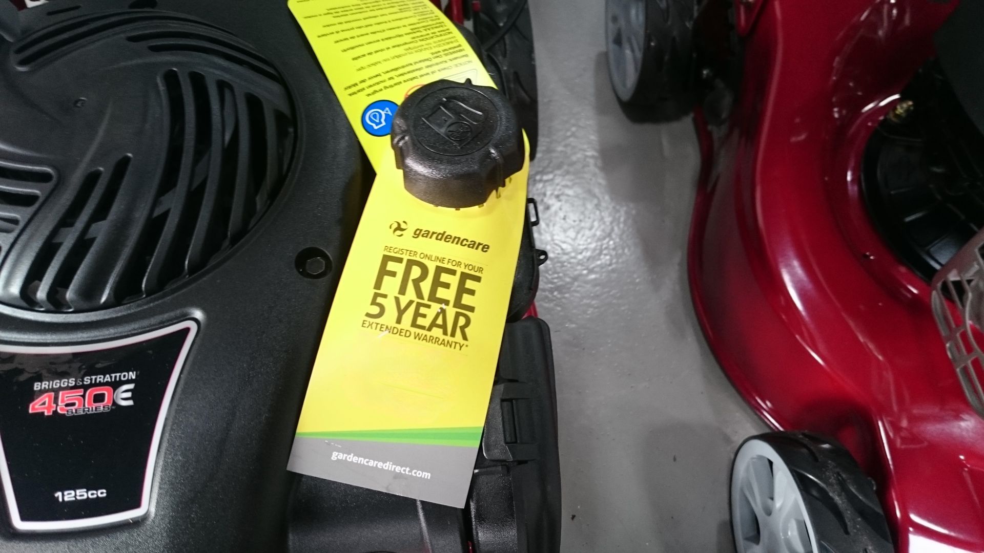 Photograph of a Gardencare 5-Year Guarantee Registration Card attached to a petrol lawnmower.