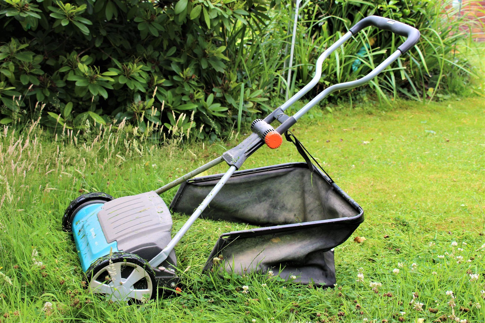 Photograph of a hand propelled Gardena cylinder mower, with grass bag.
