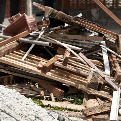 Pile of construction debris, including wood planks, metal pipes, and a brown planter.