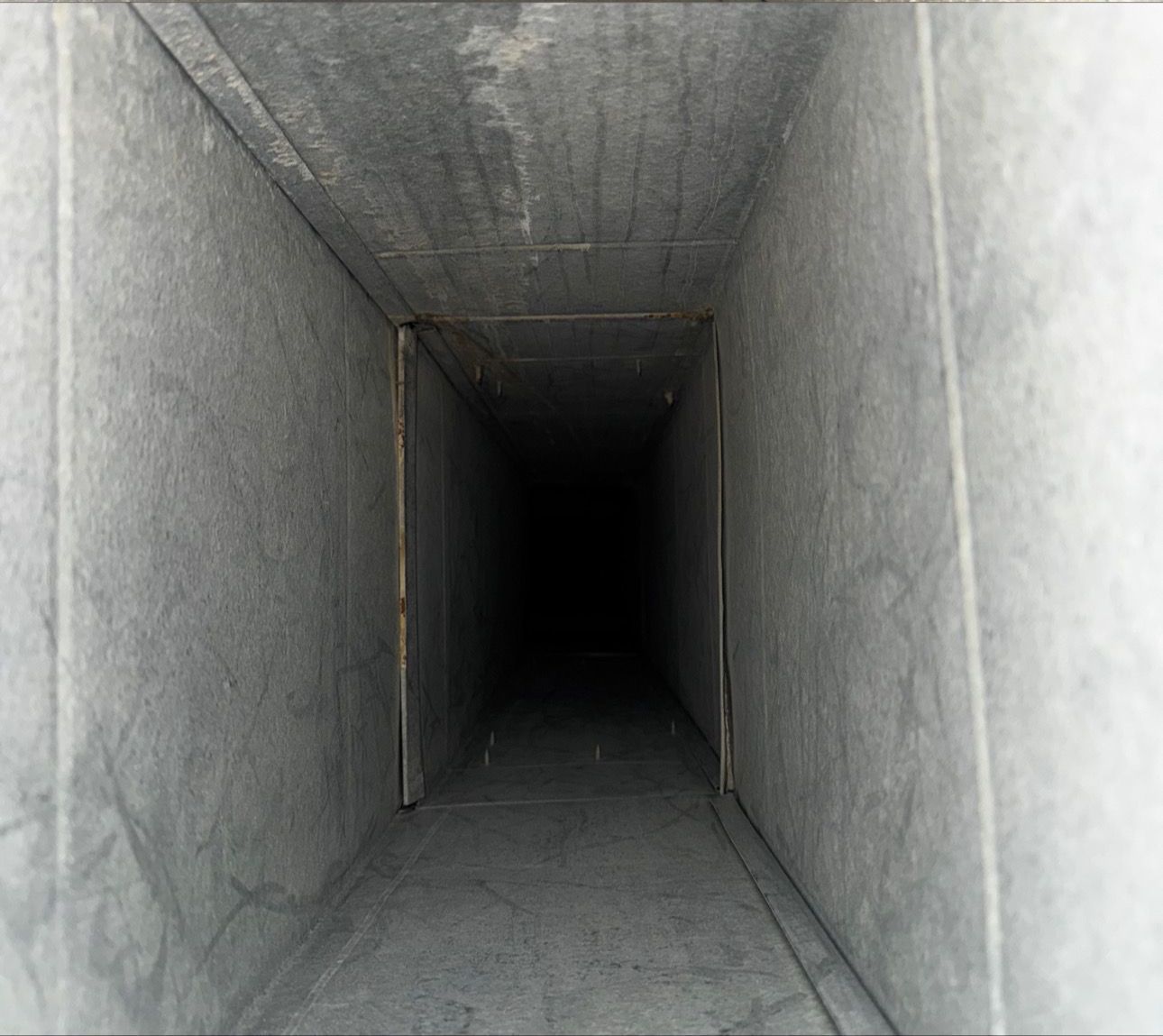 A very long concrete tunnel with a dark end.
