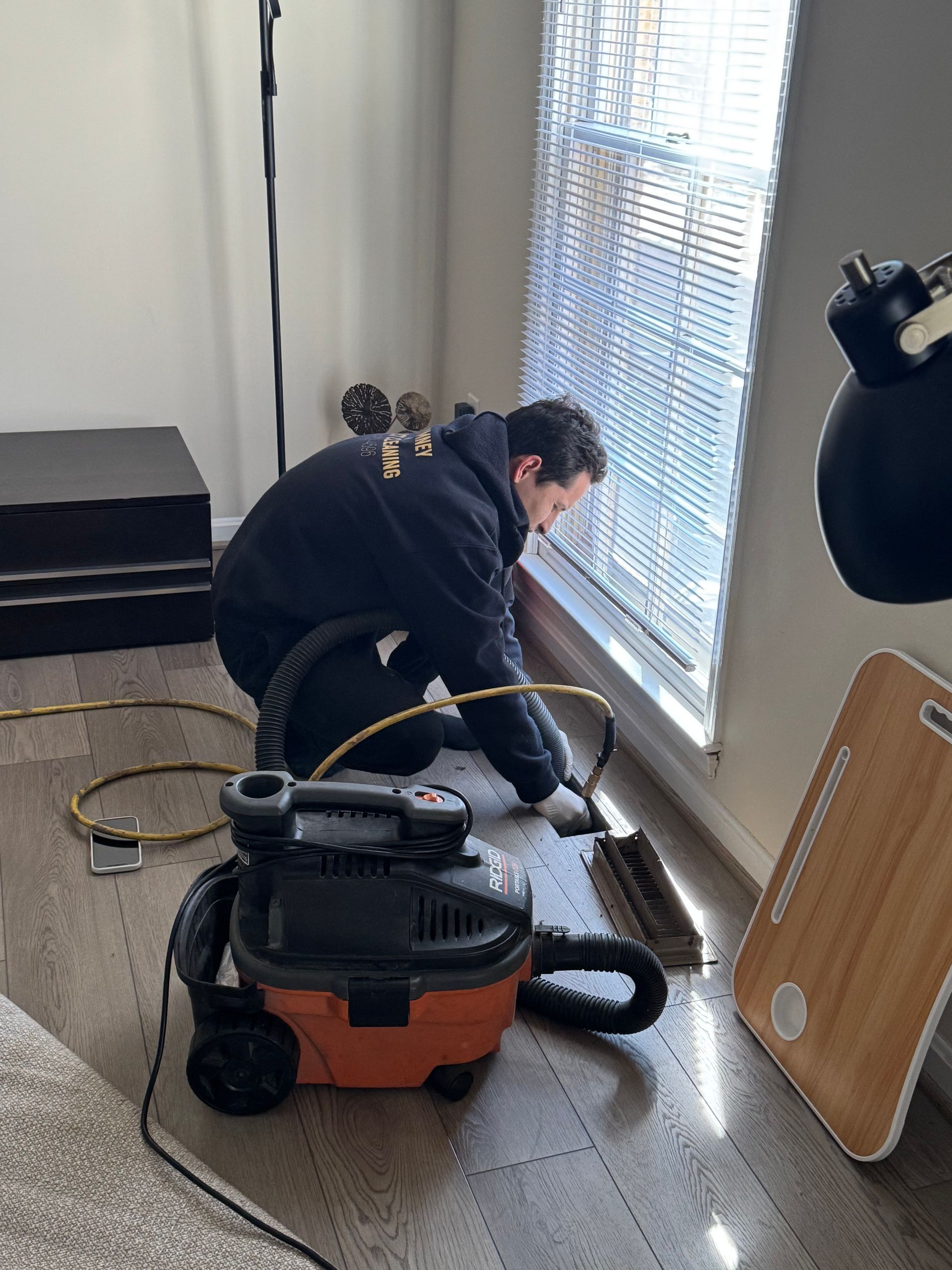 A man is cleaning the floor with a vacuum cleaner.