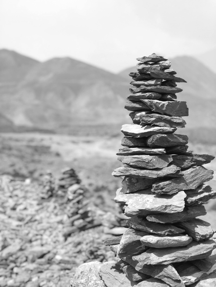 Stack of flat stones, a cairn, with blurred mountain landscape in the background.