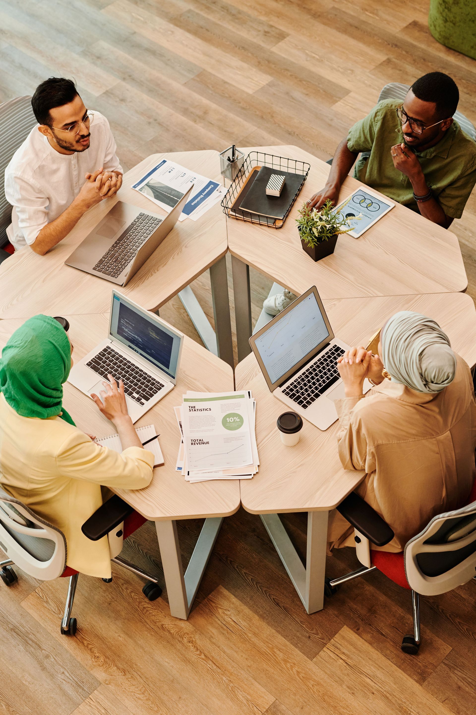 Team meeting around a round table with laptops and papers in a bright office room