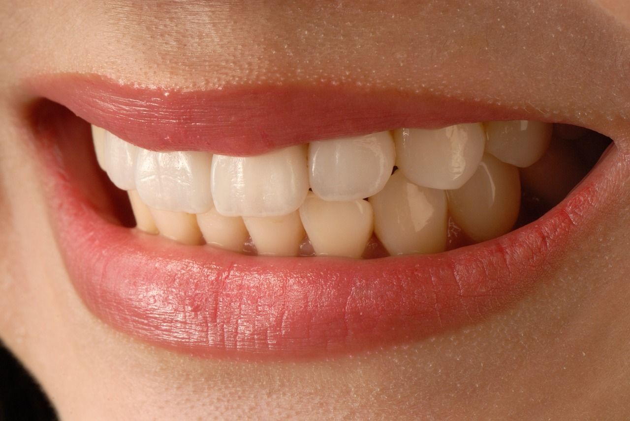 A close up of a woman 's mouth with white teeth and red lips.