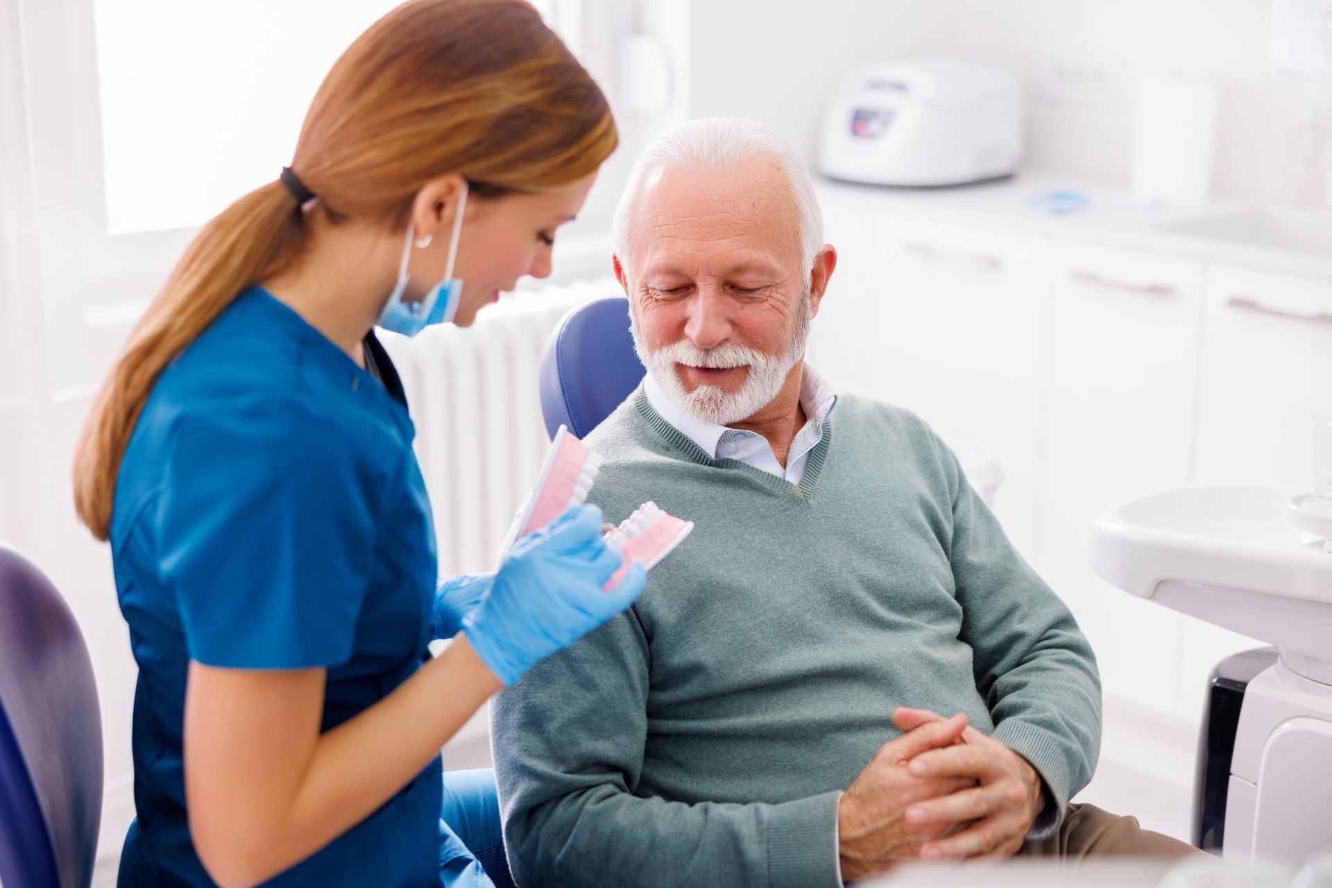 an elderly man is sitting in a dental chair while a dentist examines his teeth.