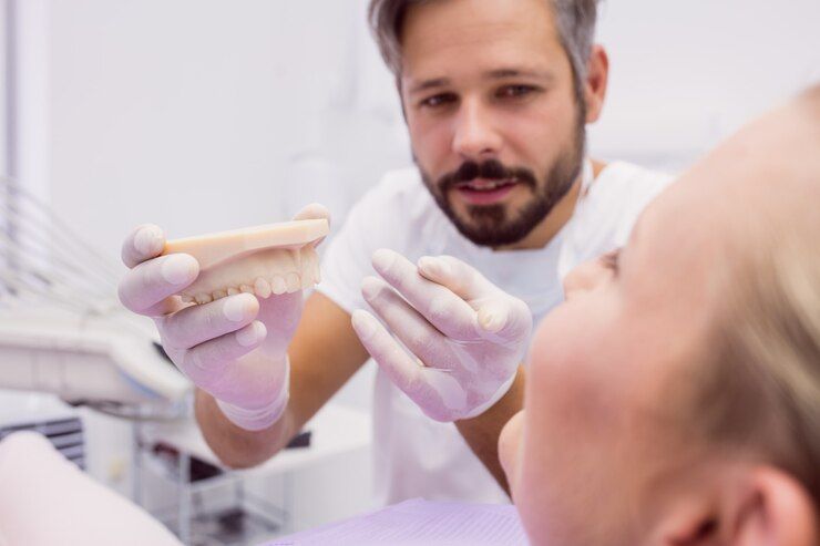 a dentist is showing a woman a model of her teeth.