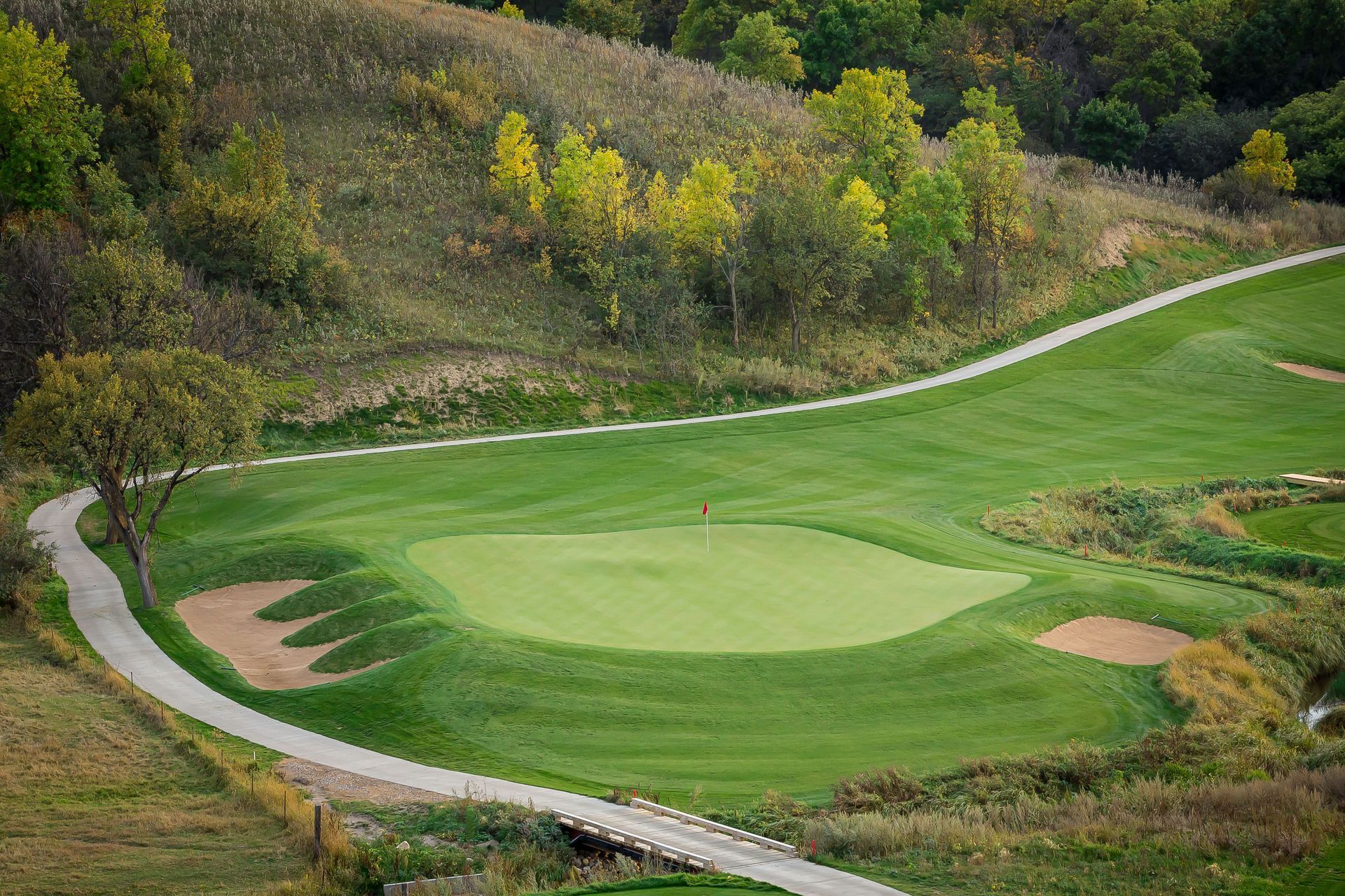 An aerial view of a golf course with a path leading to the green.