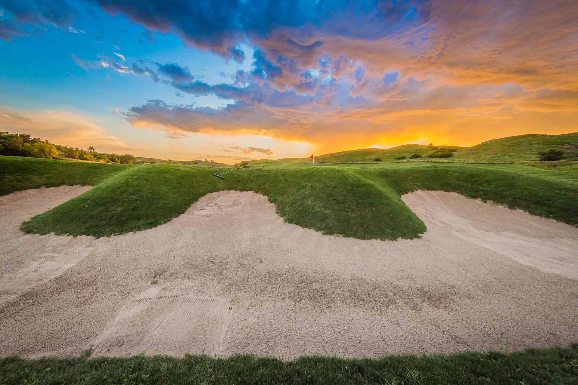 A bunker on a golf course with a sunset in the background.