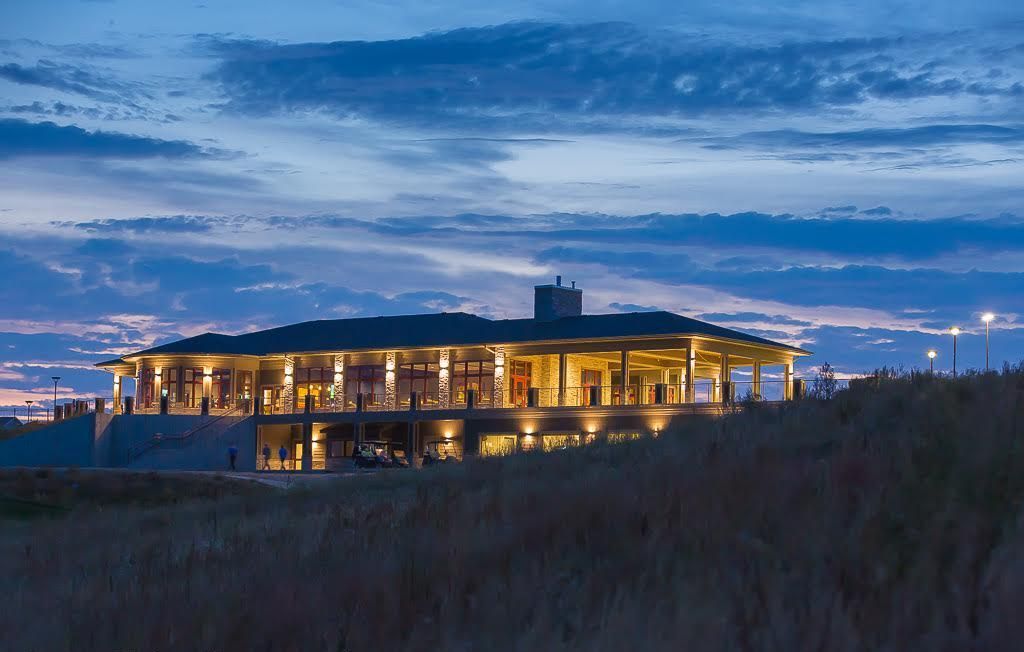 A golf ball is sitting next to a golf club on a green.