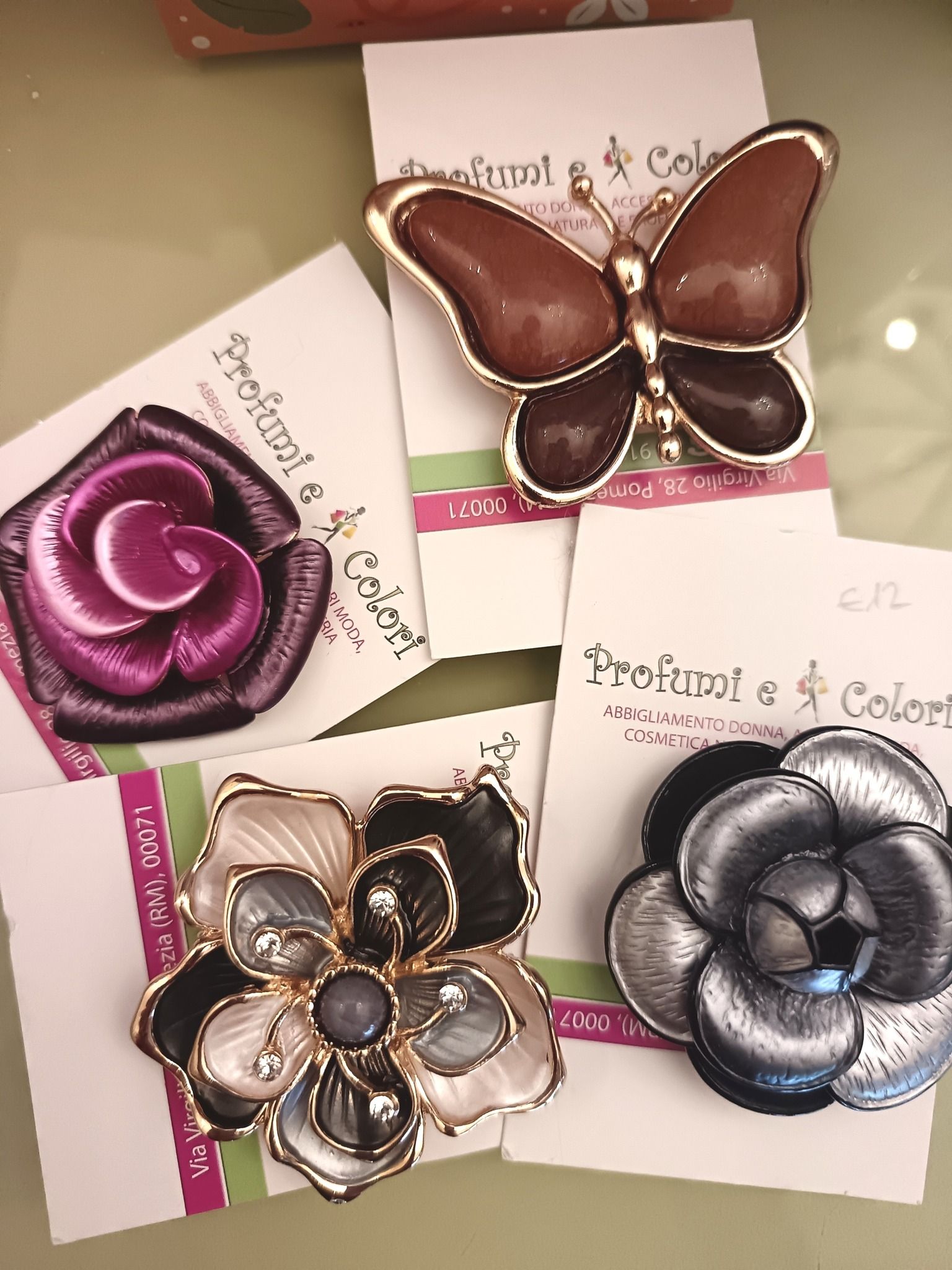 Spille su cartoncino: a forma di farfalla, rosa e fiore, in vari colori con accenti dorati, su una superficie chiara.