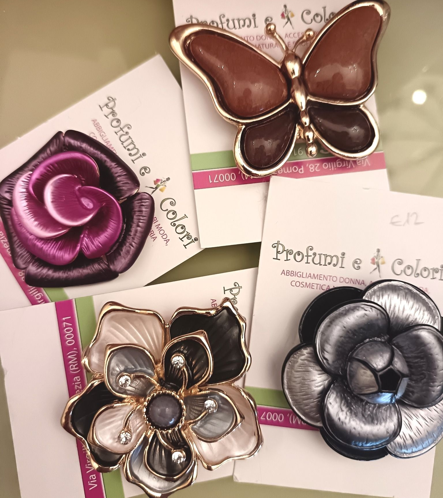 Quattro spille decorative: motivi a rosa, farfalla e fiore, vari colori, su cartoncini etichettati