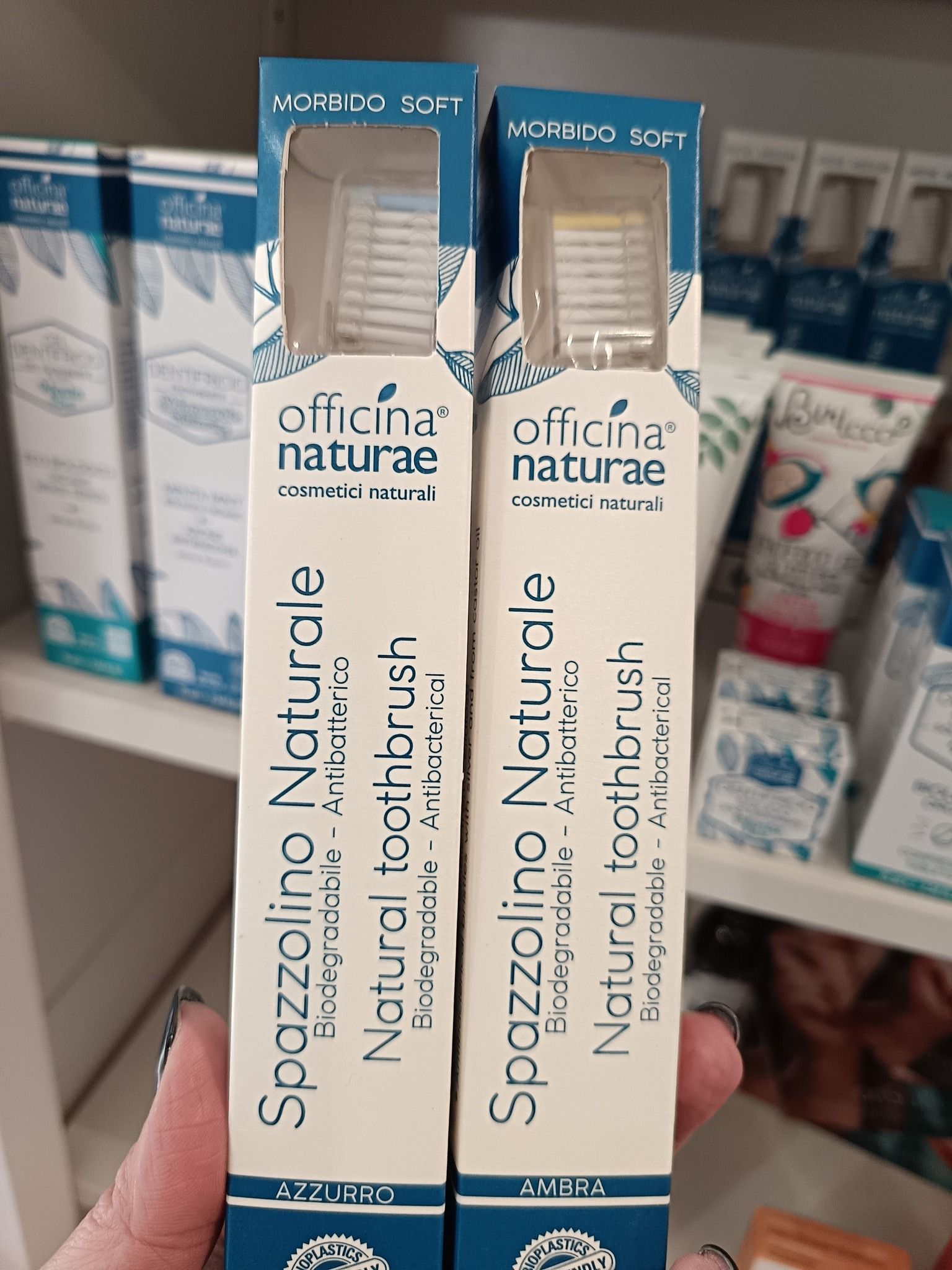 Due spazzolini da denti naturali confezionati, appoggiati a uno scaffale di prodotti simili.