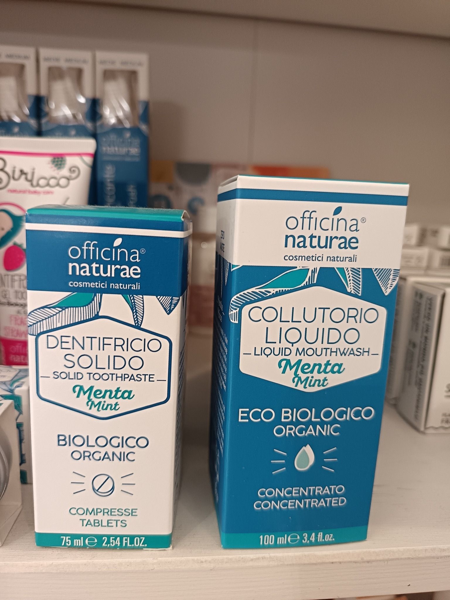 Due confezioni di prodotti Officina Naturae: dentifricio solido e collutorio liquido, entrambi al gusto di menta e biologici.