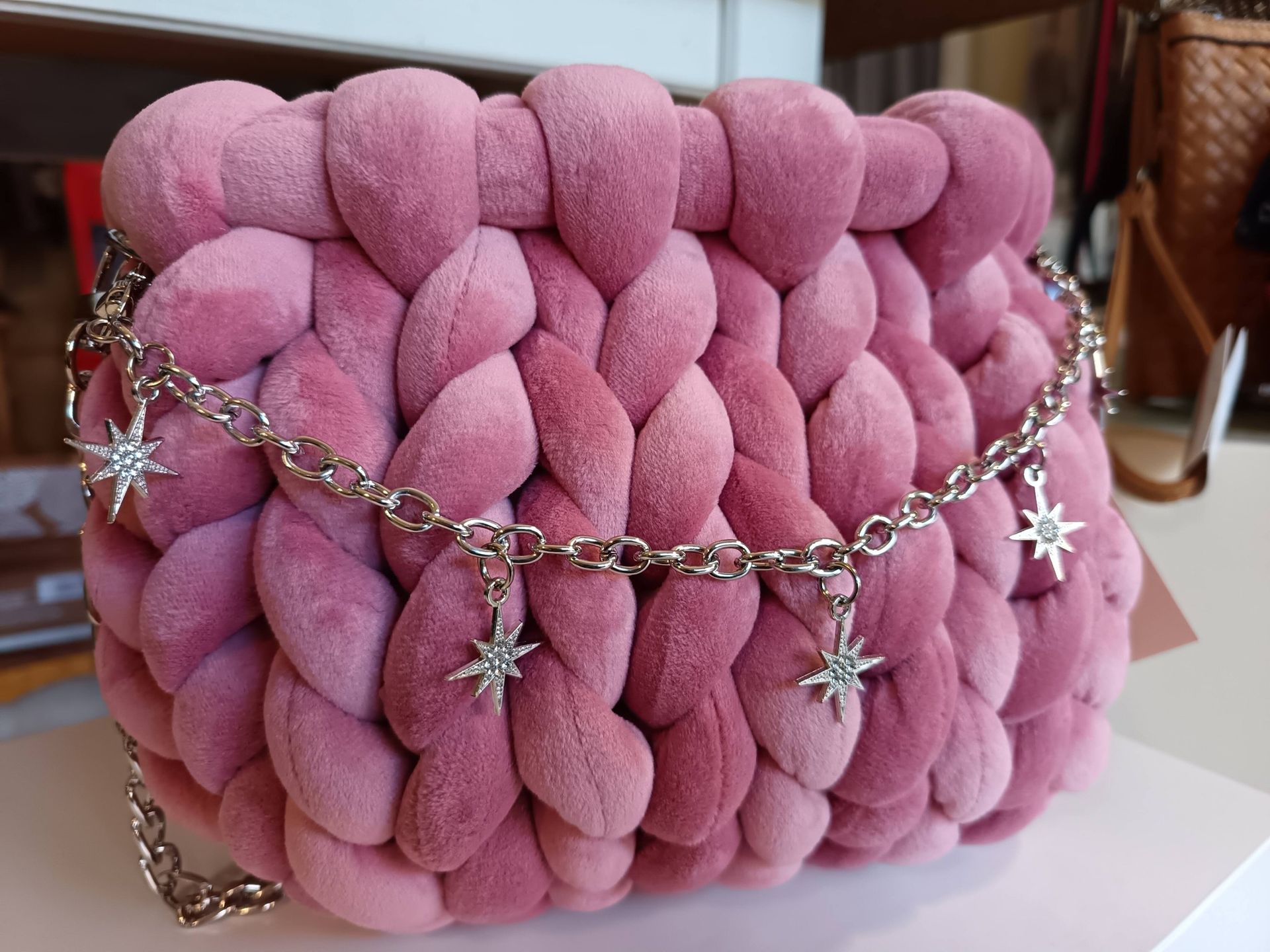 Borsa rosa lavorata all'uncinetto con tracolla a catena argentata e ciondoli a forma di stella.