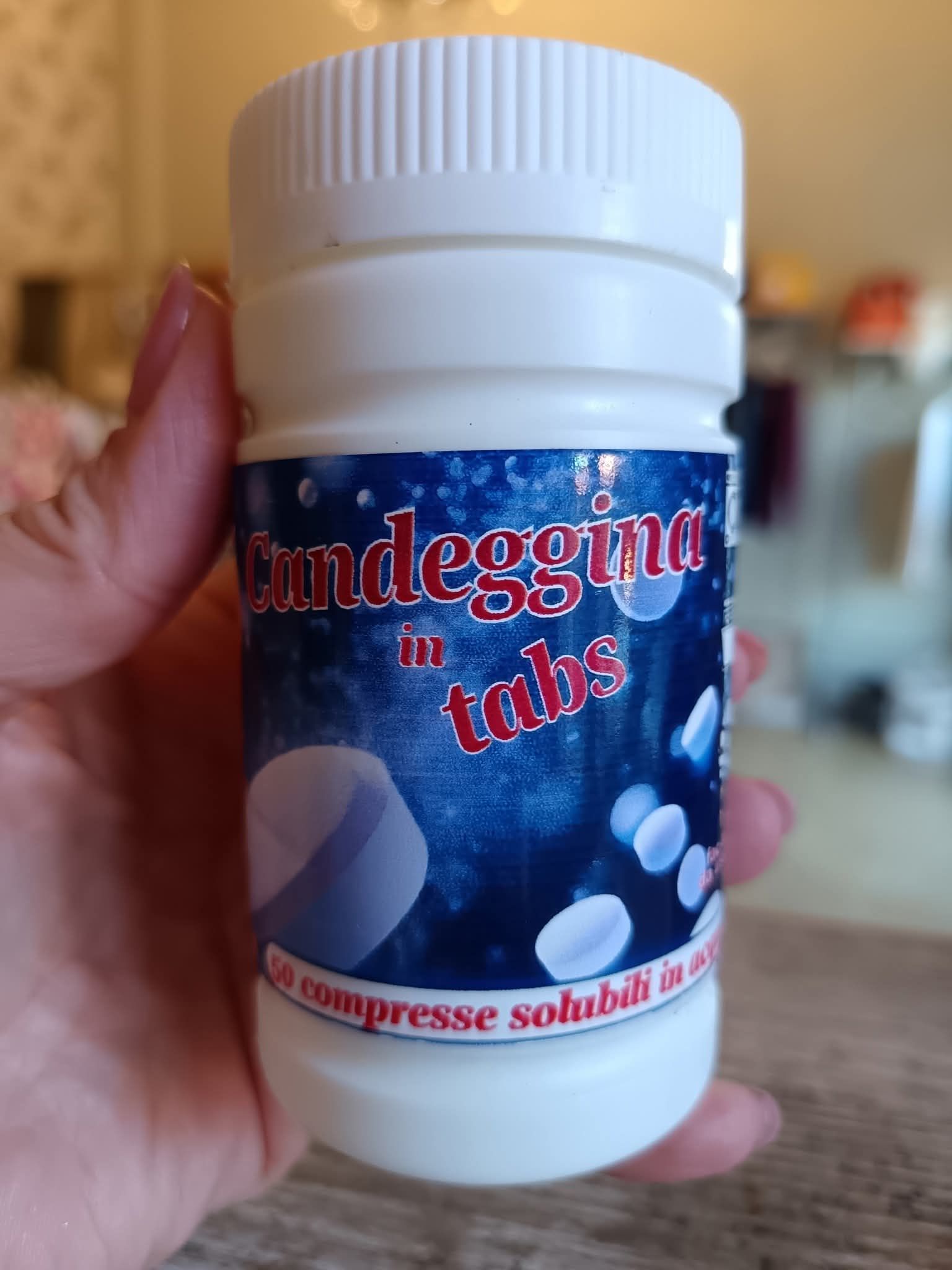 Mano che tiene una bottiglia bianca di 