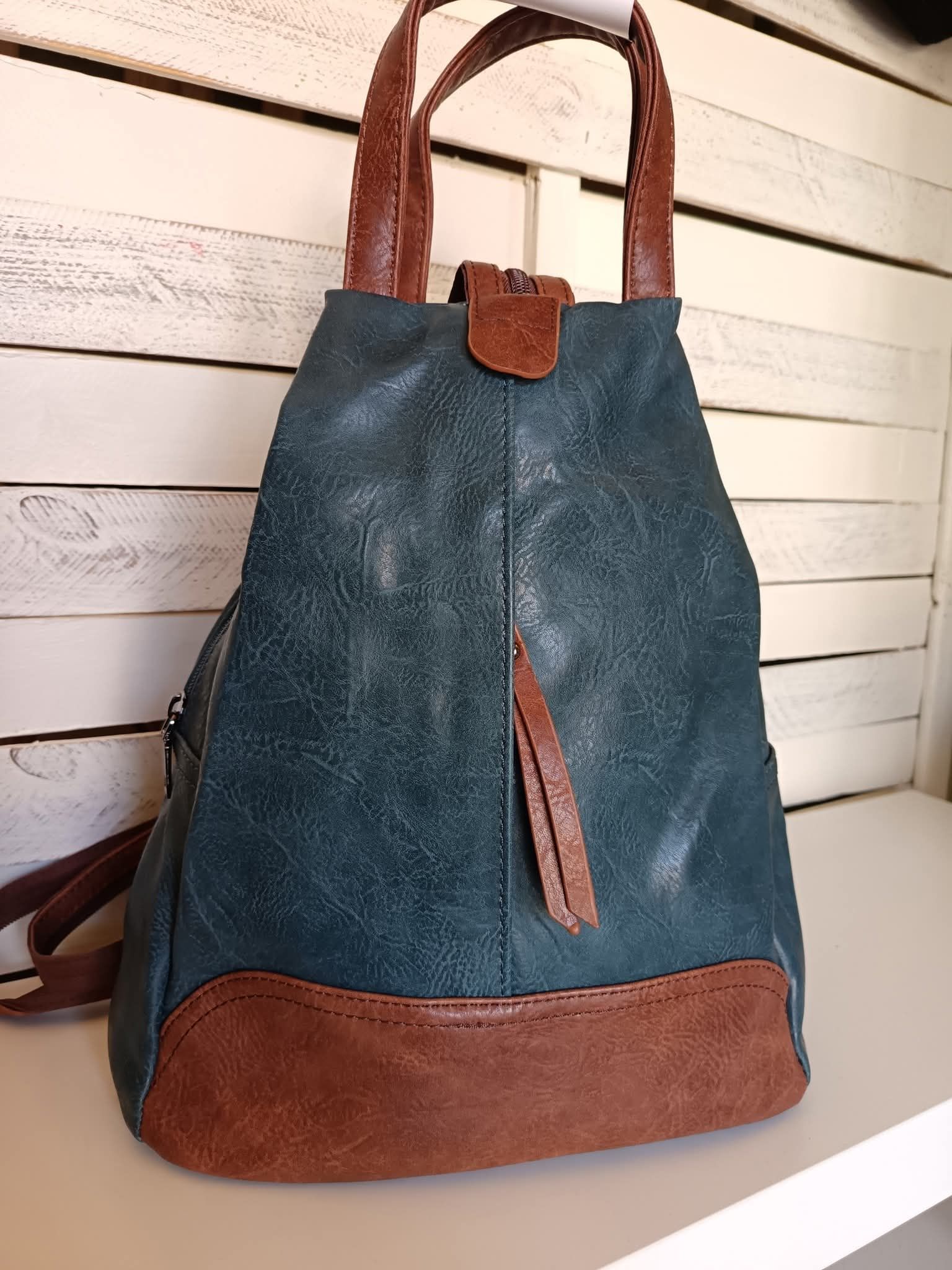 Zaino in pelle verde acqua e marrone con manico superiore.