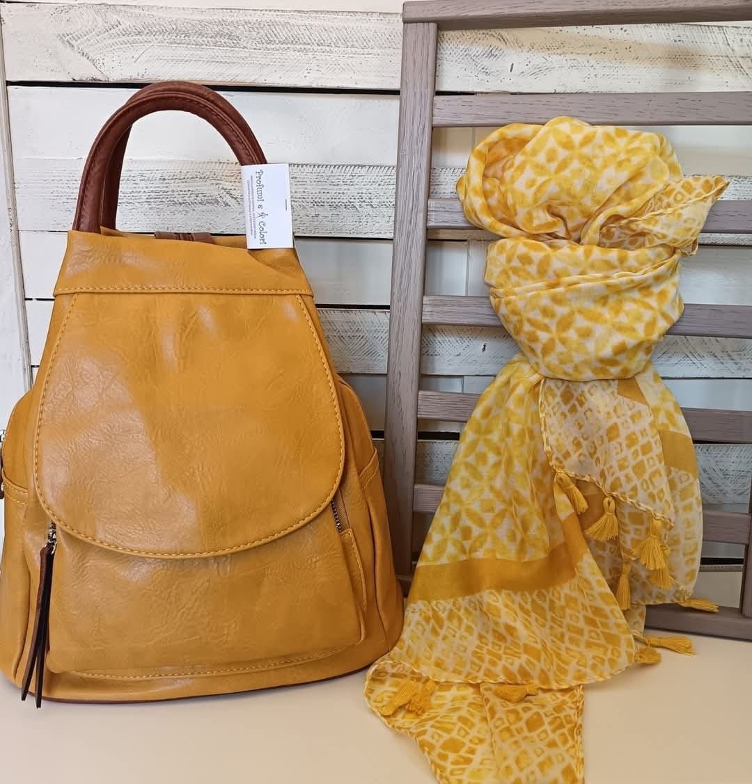 Zaino in pelle gialla con manico marrone e sciarpa gialla abbinata.