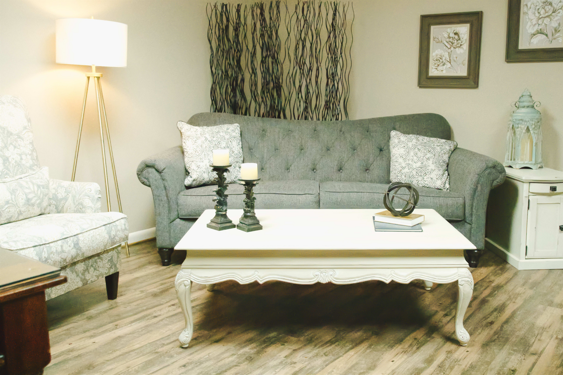 A living room with a couch , chair , coffee table and lamp.