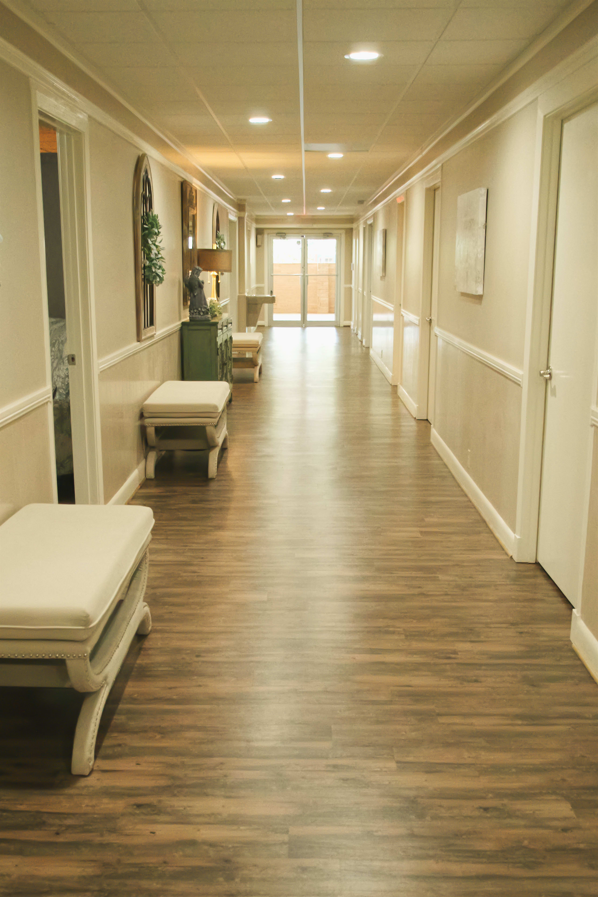 A long hallway with wooden floors and white benches.
