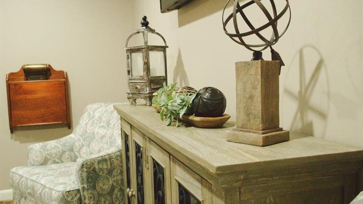 A living room with a chair and a dresser with a globe on top of it.