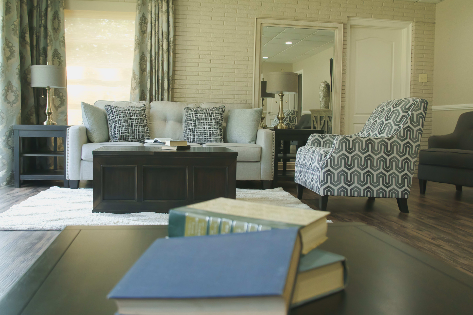 A living room with a couch , chair , coffee table and books on the table.
