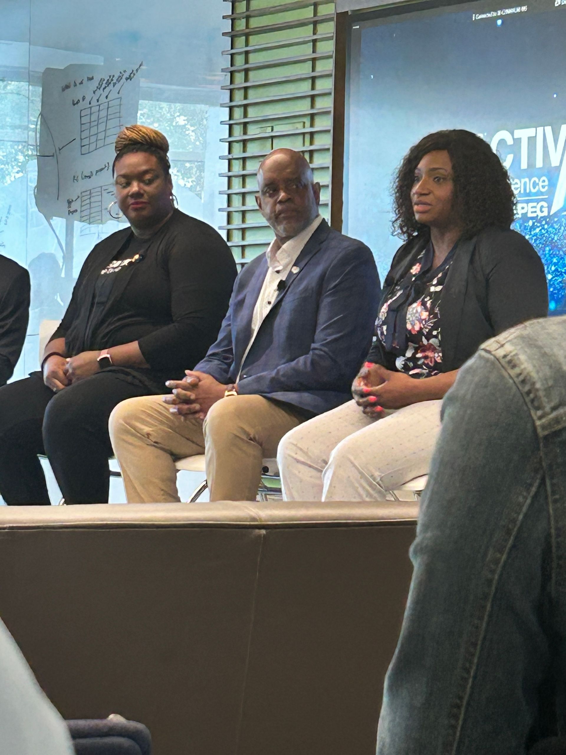 two women and a man sitting on stage