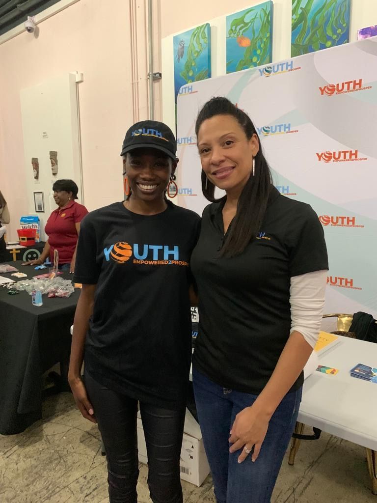 two women pose in front of a backdrop