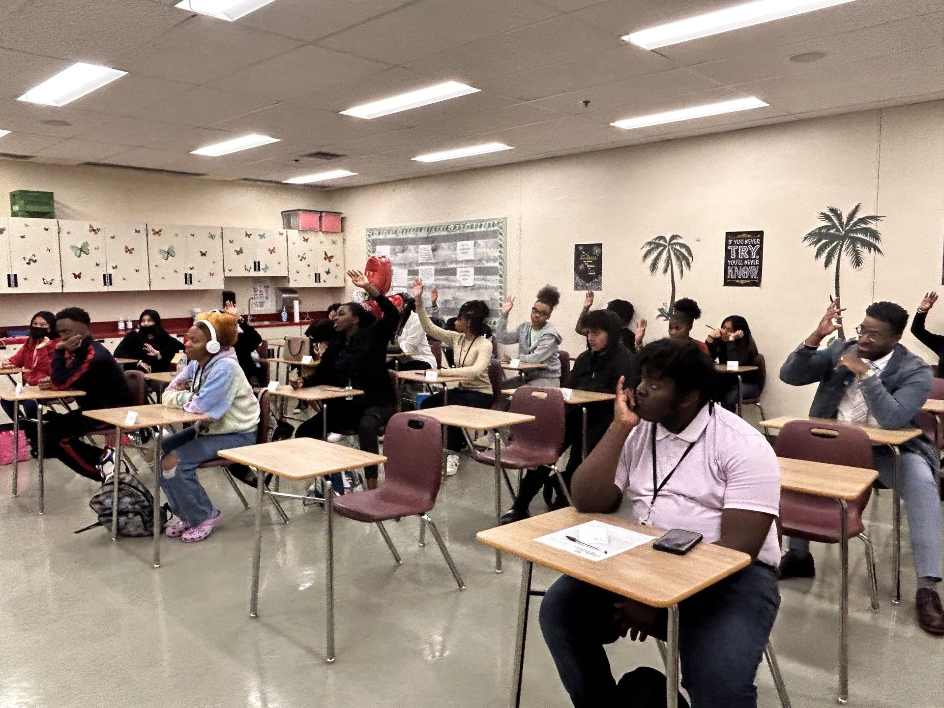 students standing at front of class listening to teacher