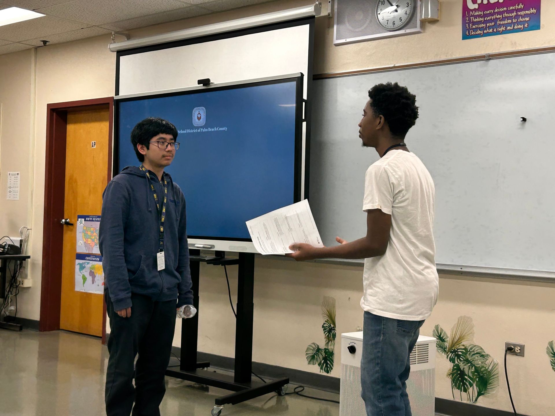 two men standing up in front of class