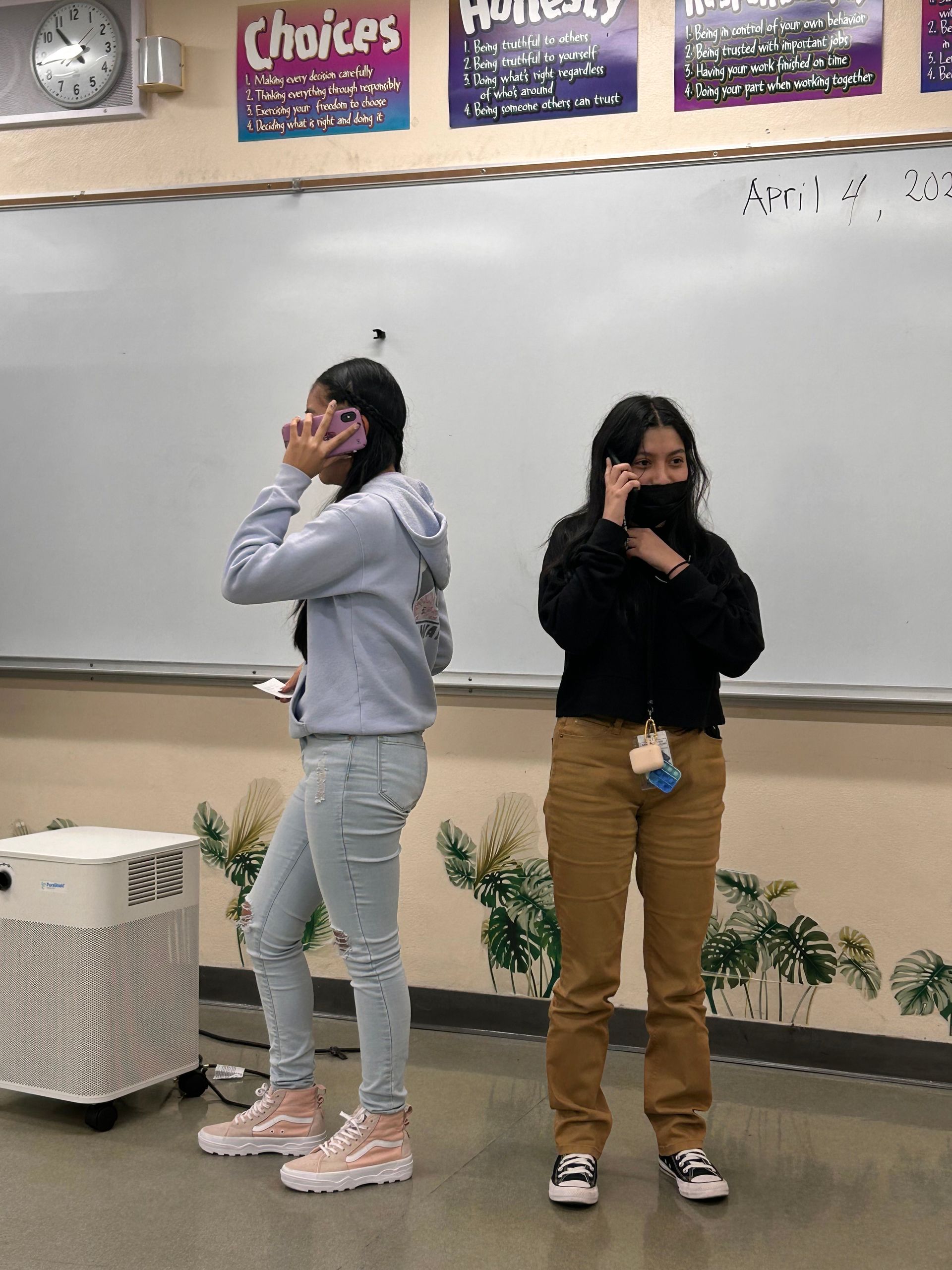 two women talking on cell phones in a classroom