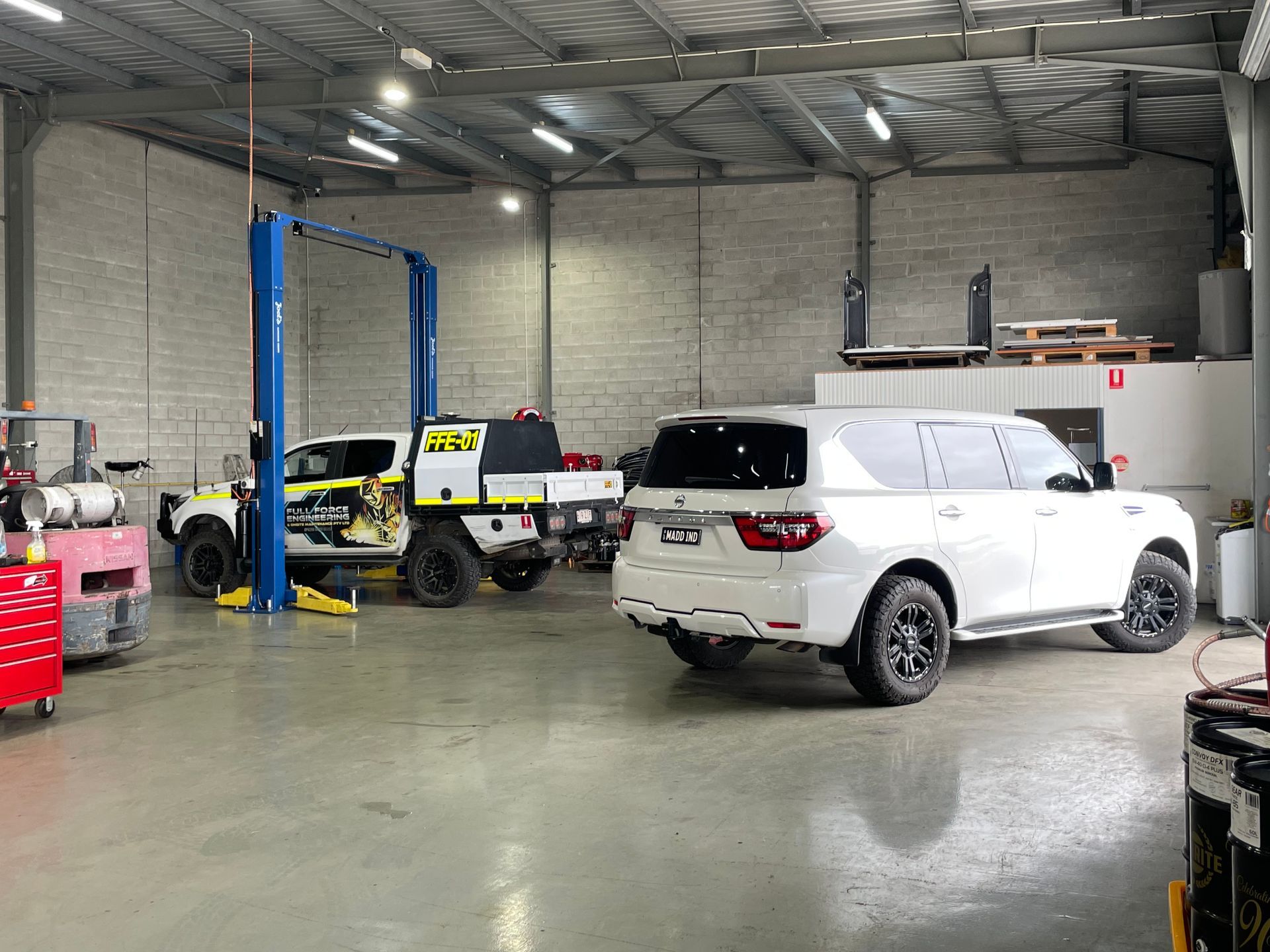 A white suv is parked in a garage next to a forklift.