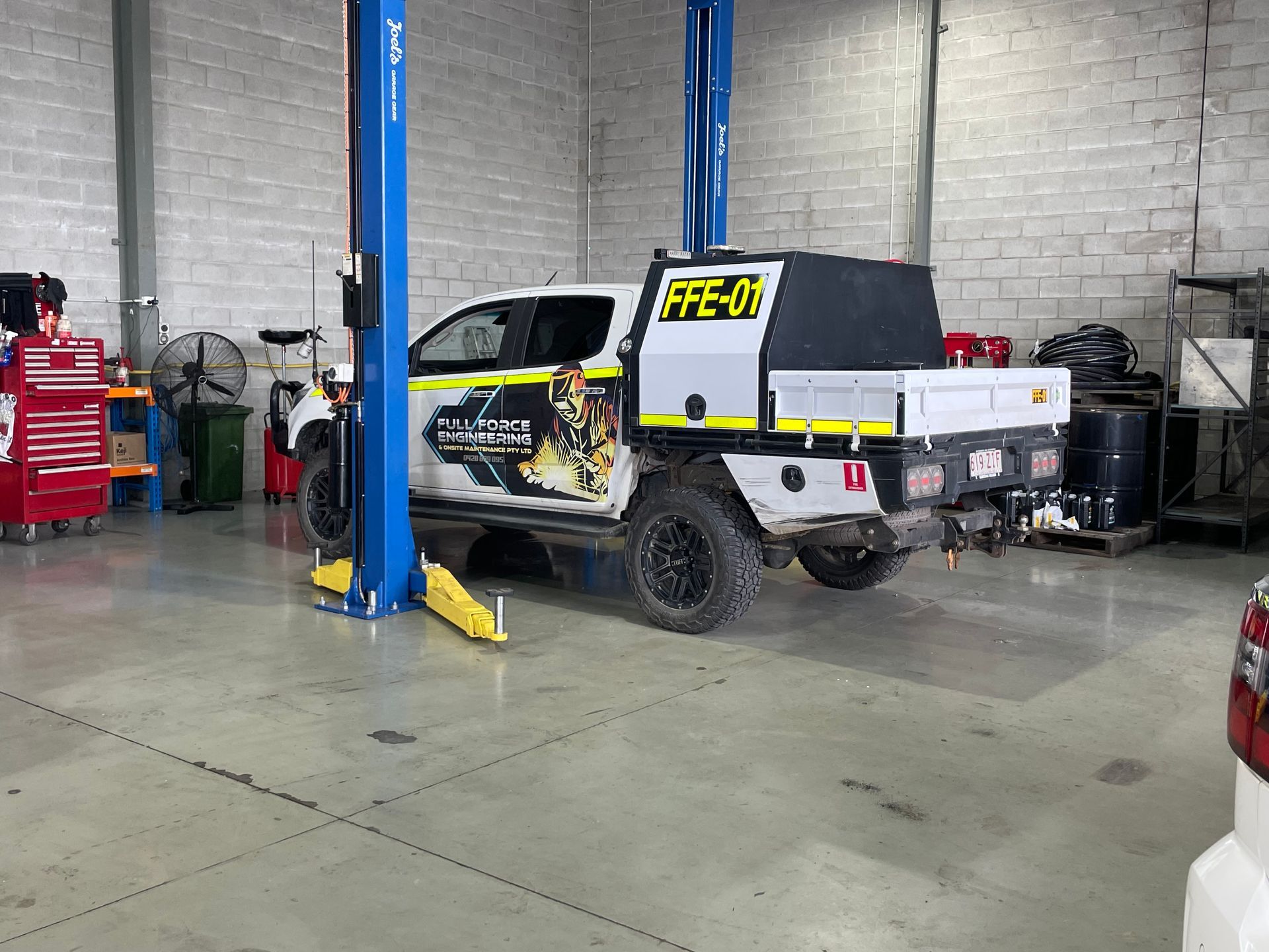 A truck is sitting on a lift in a garage.