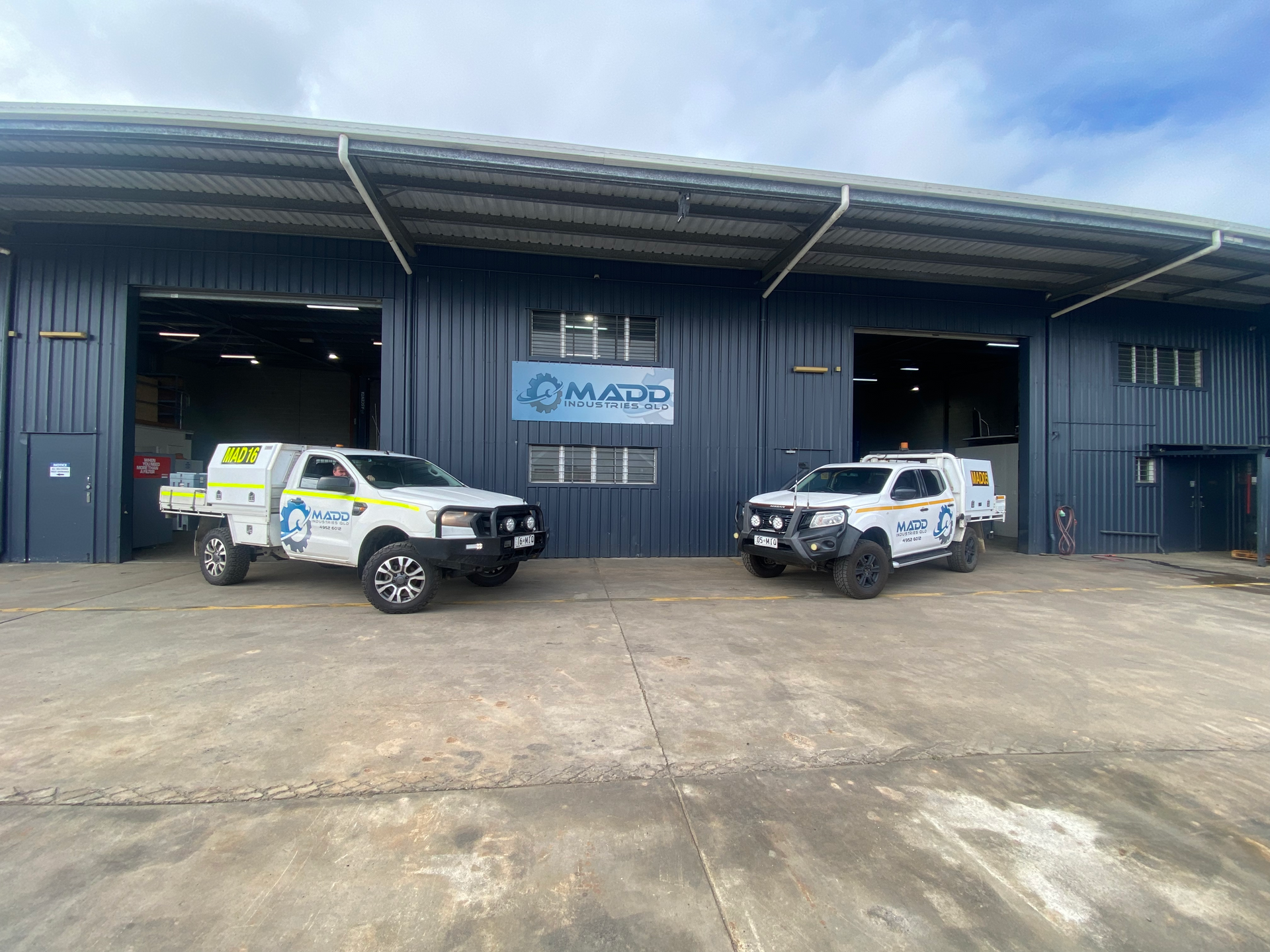 Two white trucks are parked in front of a building.