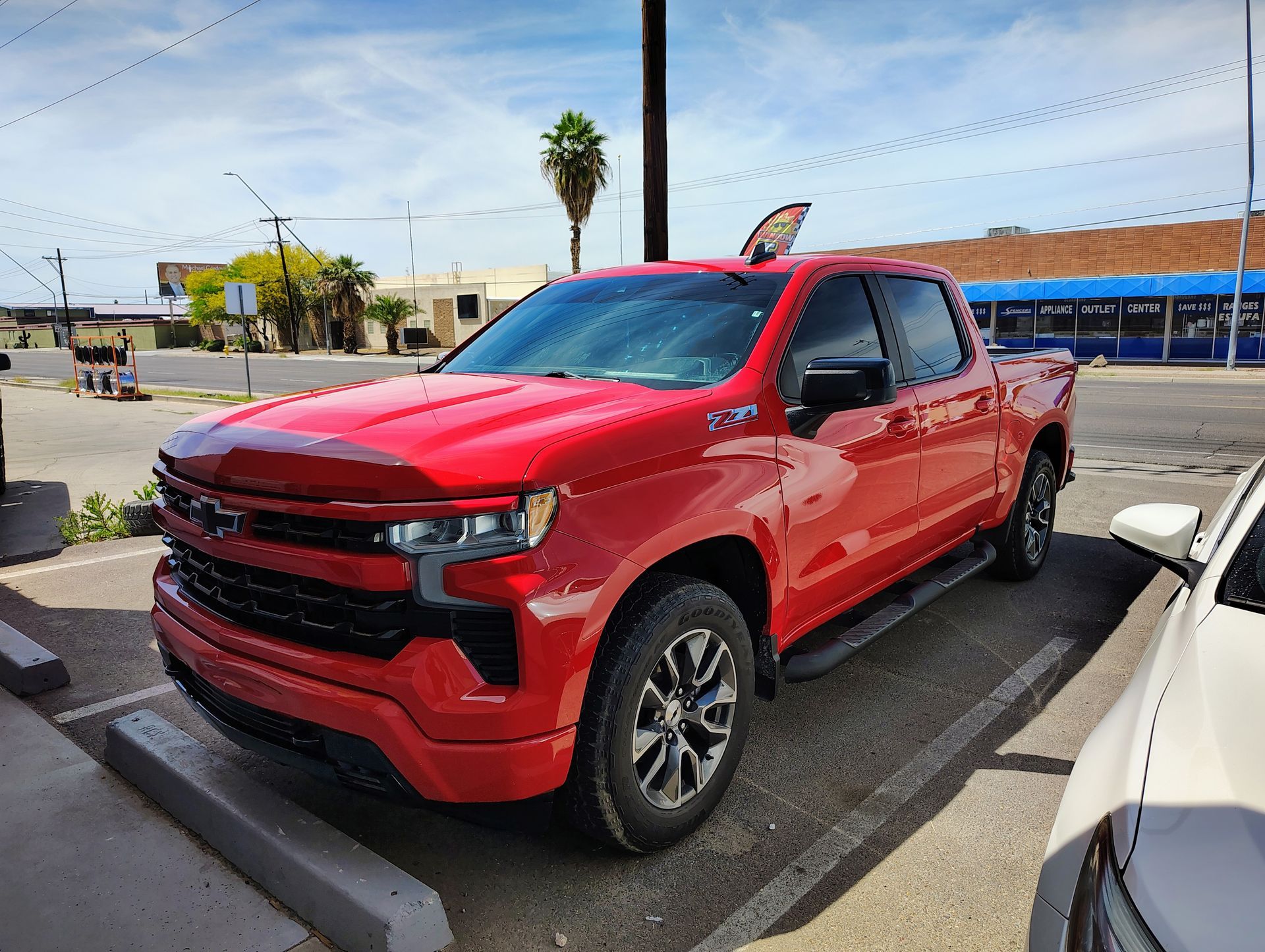 A red truck is parked in a parking lot next to a white car.