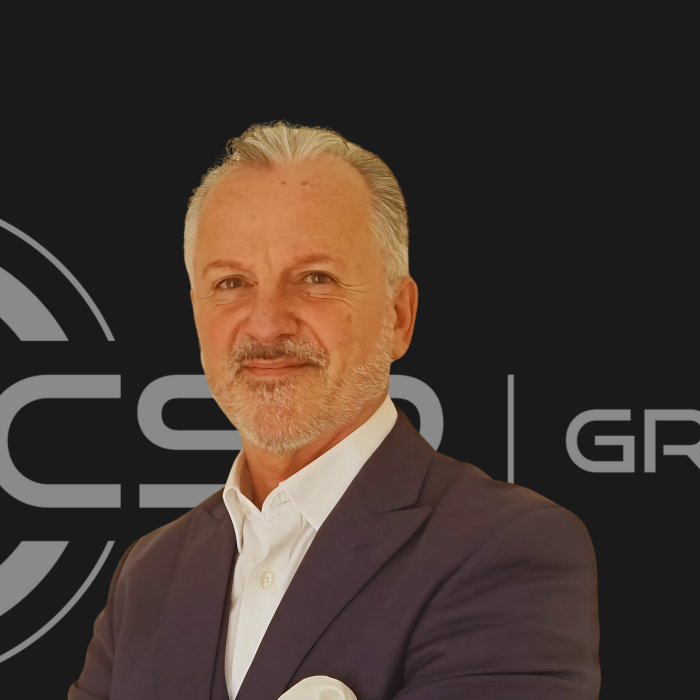 A man in a suit stands in front of a cs logo