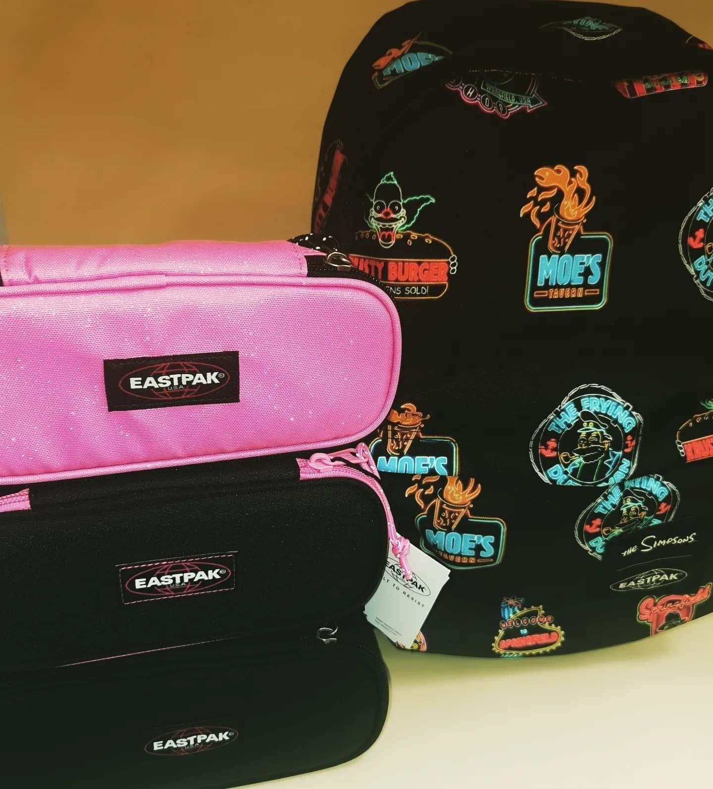 uno zaino nero di fianco a uno zaino rosa e un astuccio eastpak