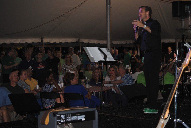 Priest speaking on stage.